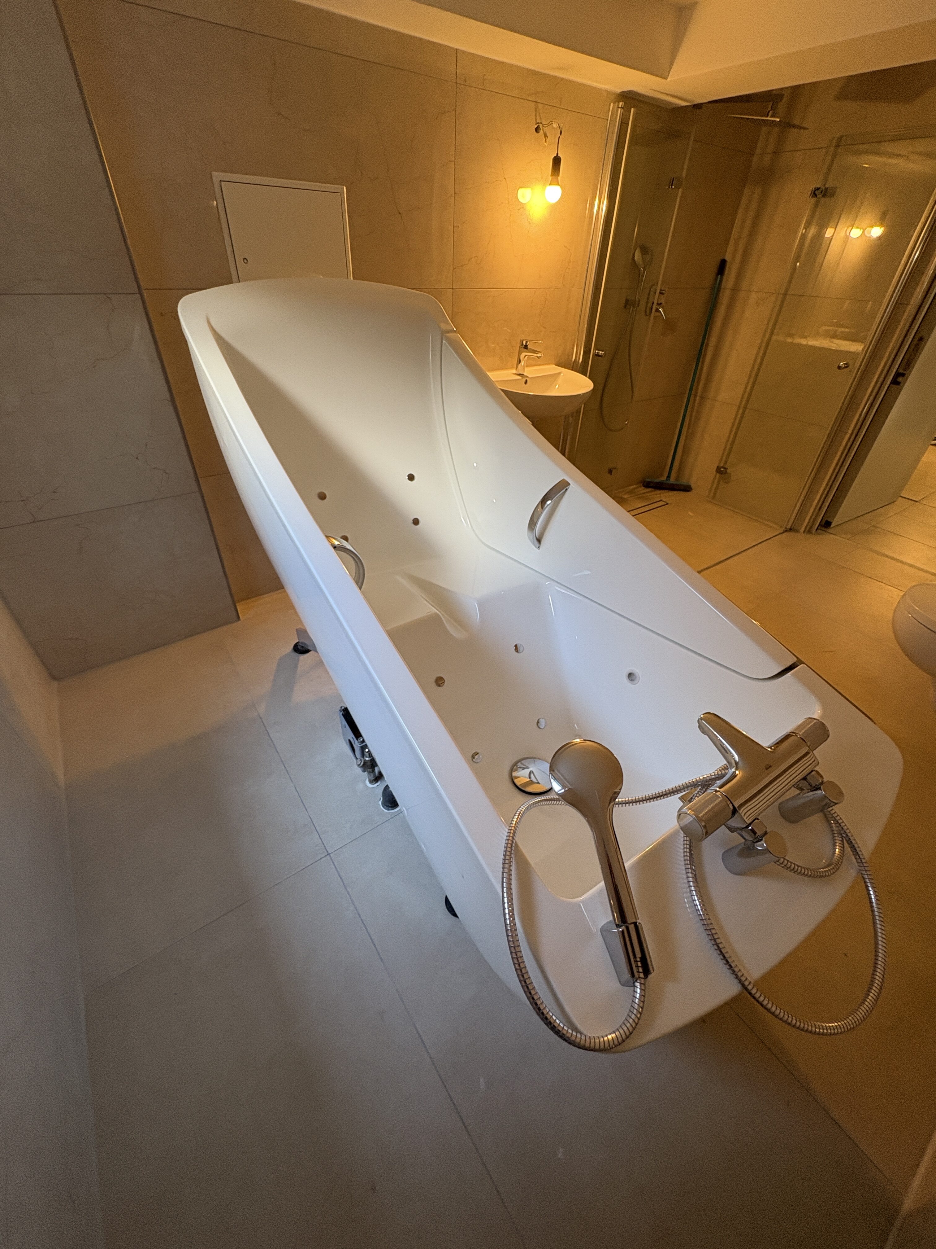 Modernes Badezimmer mit weißem Whirlpool, beigen Wänden, Dusche und dezentem Licht.